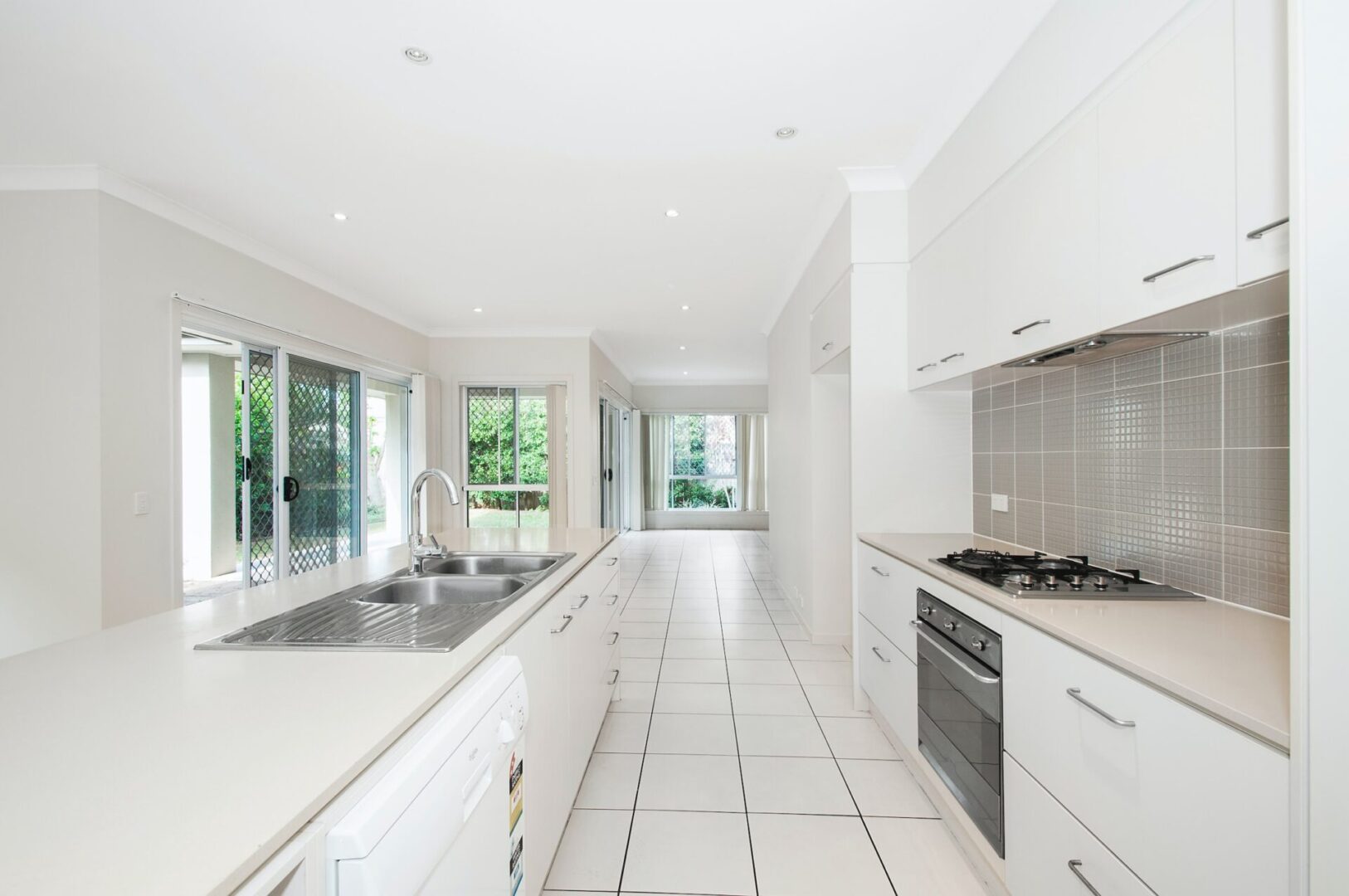 A kitchen with white cabinets and tiled floors
