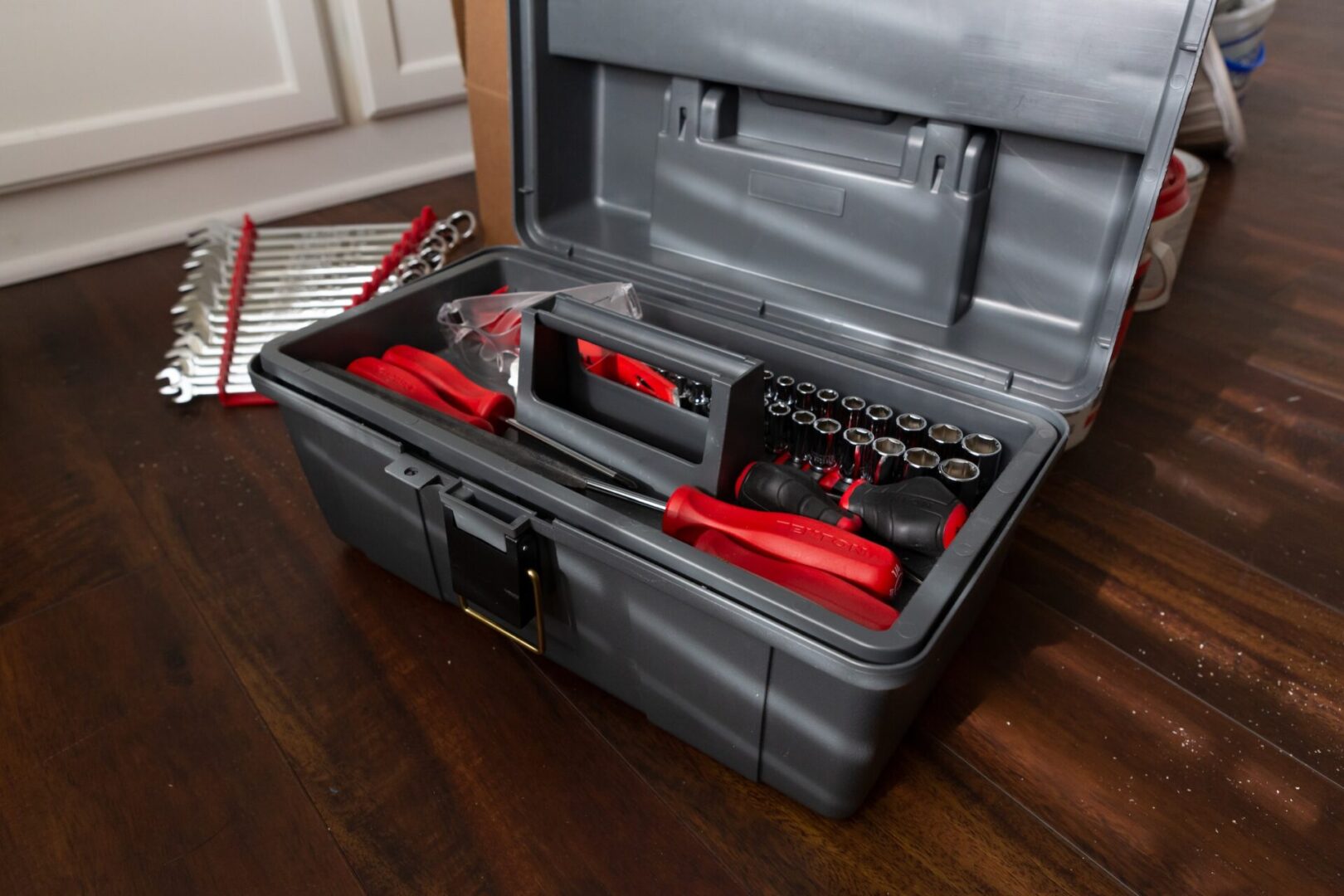 A toolbox with tools inside of it on the floor.